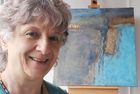Barbara Schoch steht vor einem Ihrer Gemälde und lächelt in die Kamera