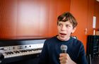 Schüler Samuel singt ins Mikrofon. Er trägt ein Lächeln auf den Lippen.
