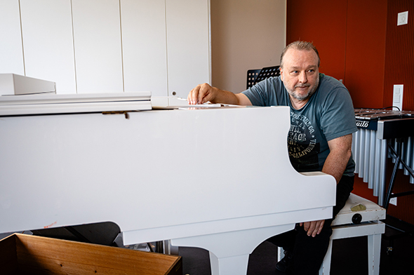 Jean-Luc Gassmann sitzt an einem weissen Klavier und erklärt einem Schüler etwas